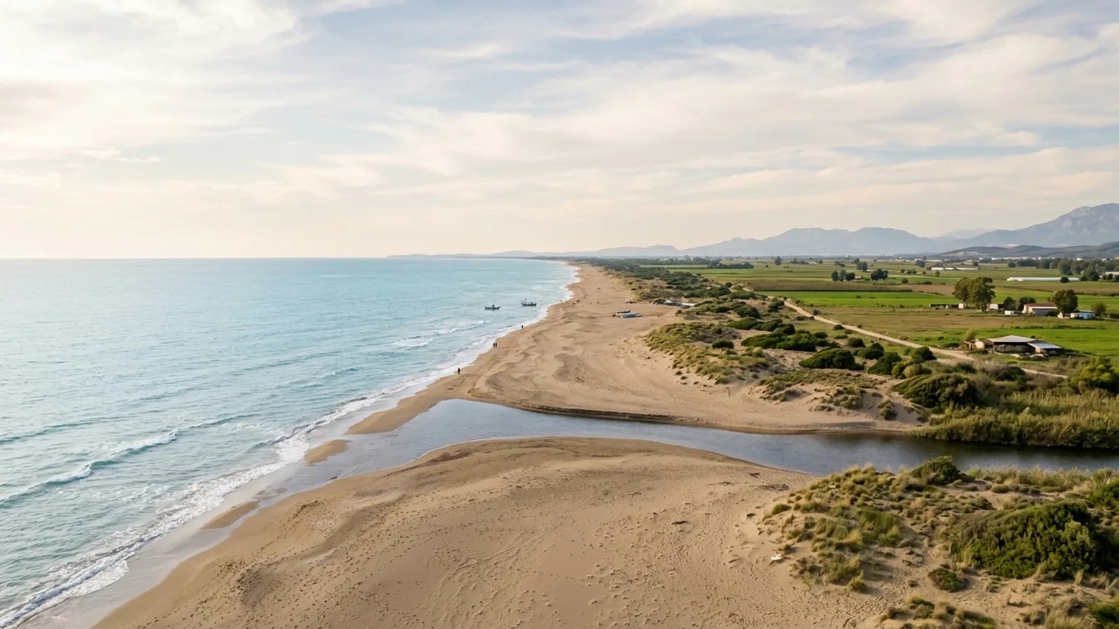 Bogazkent, Türkiye — the quiet sandy shore at Bogazkent east of Belek, a river mouth meeting the sea and flat farmland behind the dunes.