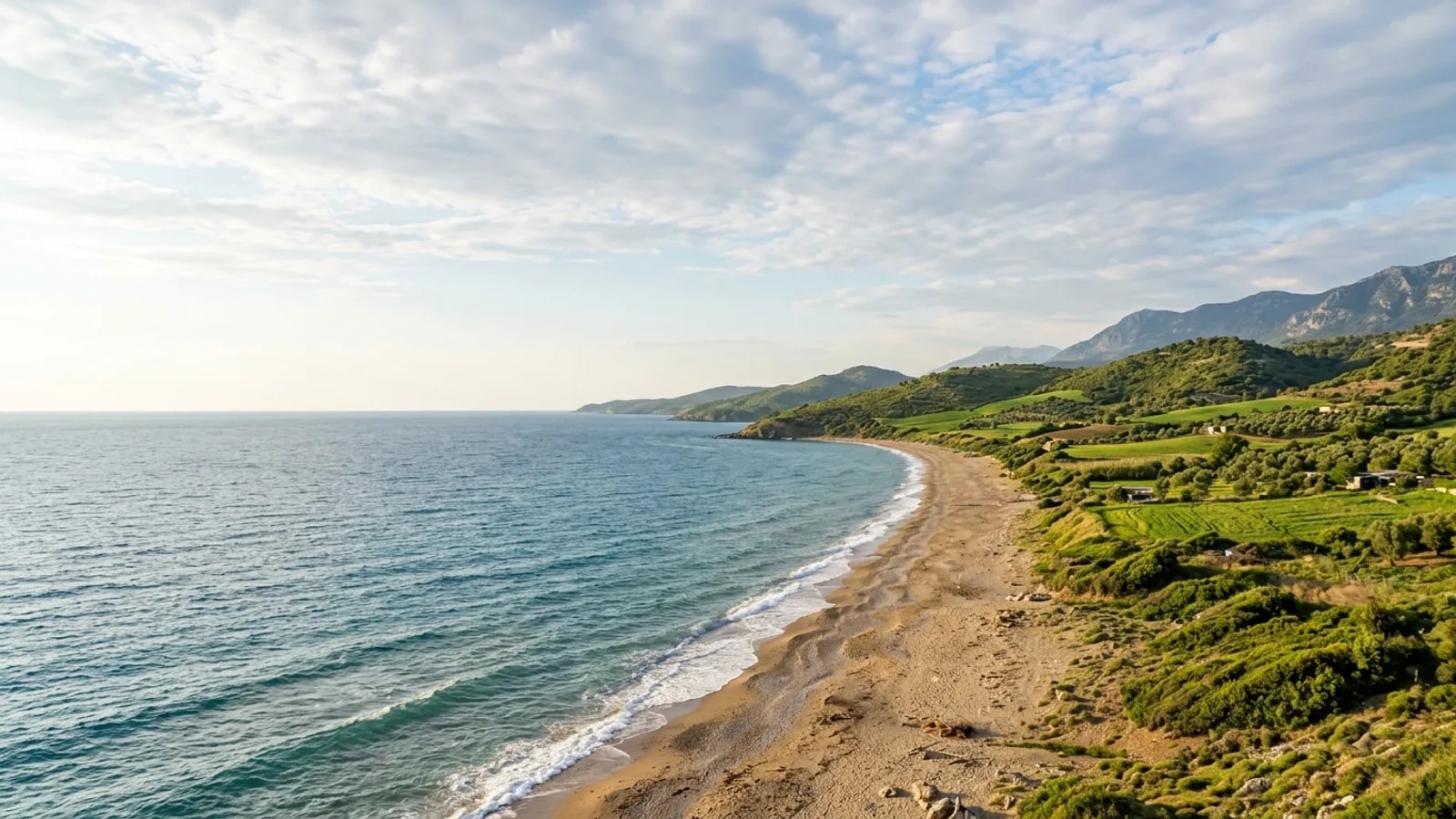 Denizyaka, Türkiye — the rural coastline near Denizyaka east of Manavgat, farmland and low green hills running down to a sandy Mediterranean shore.