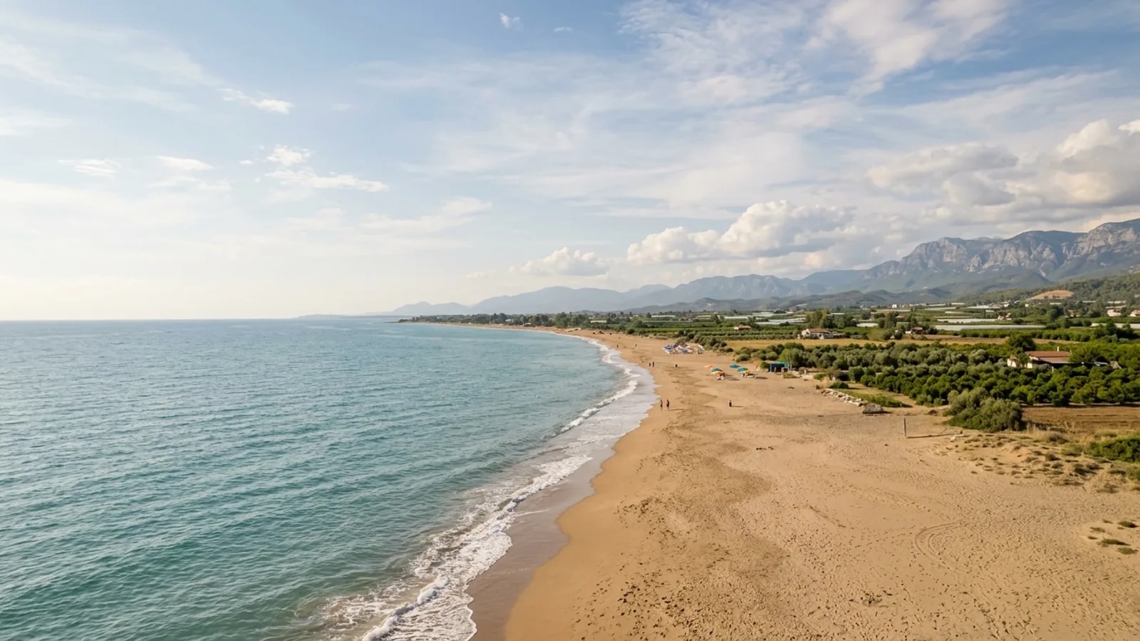 Gundogdu, Türkiye — the quiet sandy shore at Gundogdu on the coast east of Side, a flat farmed plain of orchards behind the beach.
