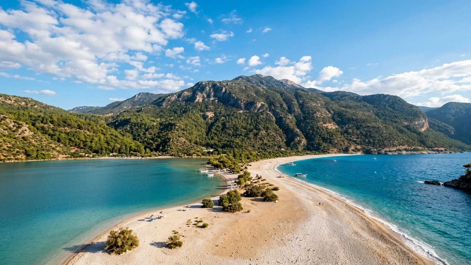 Oludeniz, Türkiye — the Blue Lagoon at Oludeniz near Fethiye, a calm turquoise lagoon behind a curving pebble spit with the steep forested Babadag mountain rising behind.