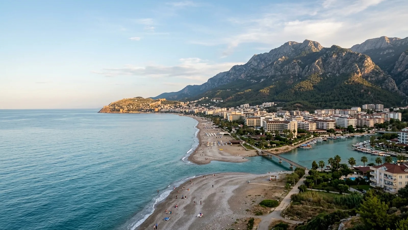 Tosmur, Türkiye — the Tosmur district east of Alanya, a pebble beach and a river mouth with the Taurus mountains rising steeply behind the town.